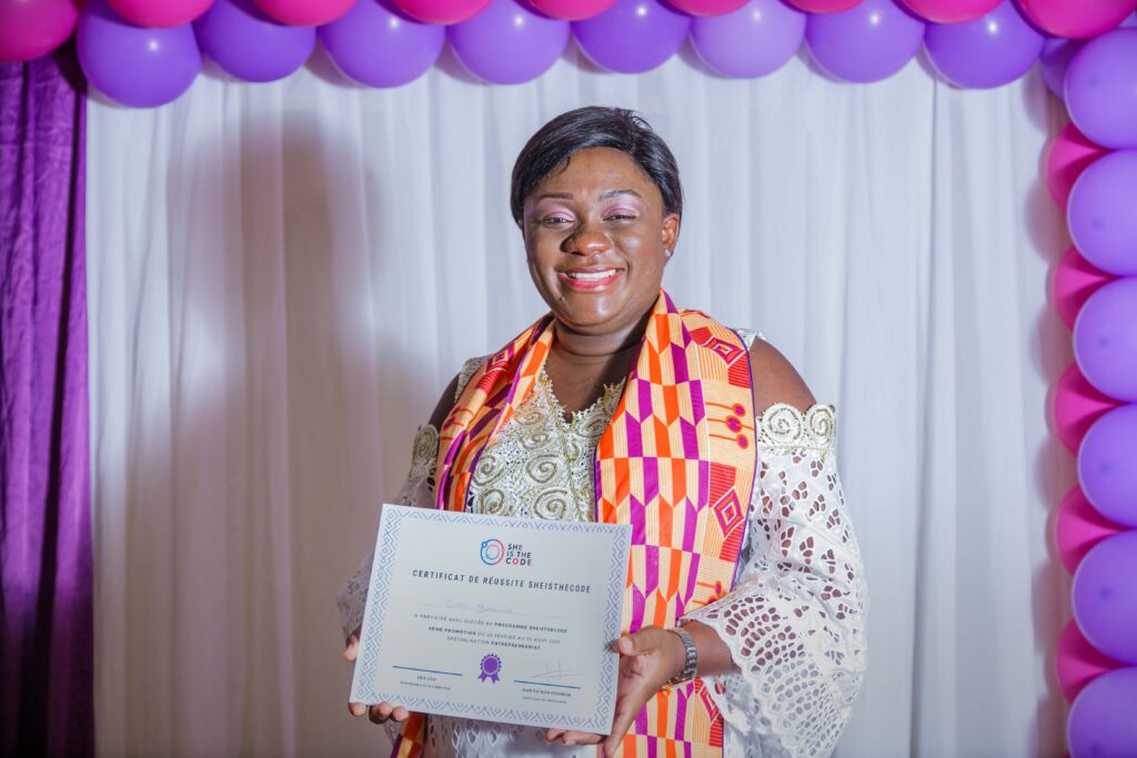 Mme Aguidissou, diplomée du programme SheIsTheCode (promotion 2021), tenant le certificat qui atteste qu'elle peut désormais agir en tant que agent de transformation digiale.